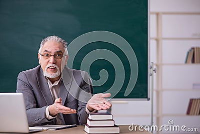 Old male teacher in front of blackboard Stock Photo