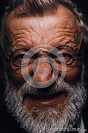 Old man with angry evil horror expression on face, close up on black background Stock Photo