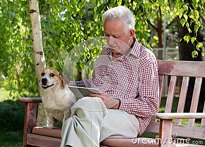 Old man with dog and tablet in garden Stock Photo