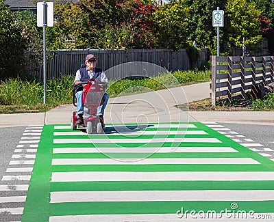 Old man driving a mobility scooter wheelchair crossing the street on a zebra Editorial Stock Photo