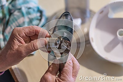 Old man grandpa with hands builds assembled disassembles a kitchen mashine into the parts, Germany Stock Photo