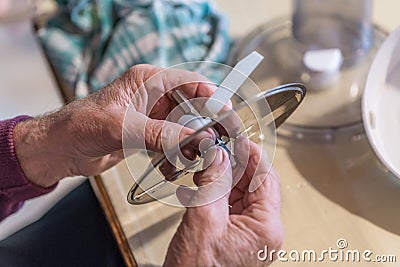 Old man grandpa with hands builds assembled disassembles a kitchen mashine into the parts, Germany Stock Photo