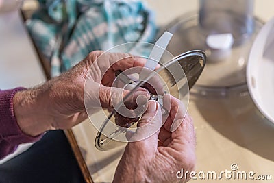 Old man grandpa with hands builds assembled disassembles a kitchen mashine into the parts, Germany Stock Photo