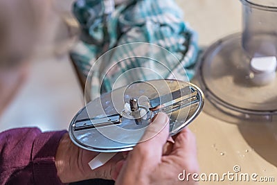Old man grandpa with hands builds assembled disassembles a kitchen mashine into the parts, Germany Stock Photo