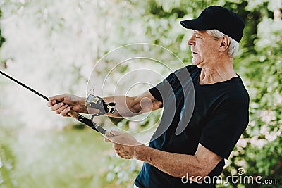 Old Man with Gray Hair Fishing on River in Summer. Stock Photo