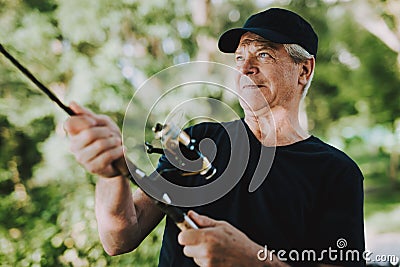 Old Man with Gray Hair Fishing on River in Summer. Stock Photo