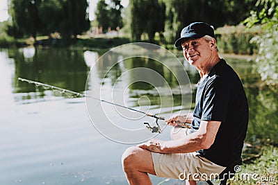 Old Man with Gray Hair Fishing on River in Summer. Stock Photo