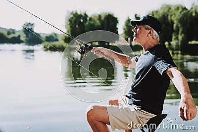 Old Man with Gray Hair Fishing on River in Summer. Stock Photo