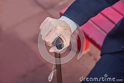 Old man hand holding walking stick outdoor Stock Photo