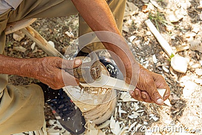 Old man handcrafting a wood spoon the traditional way of making tools in the villages of Romania and Eastern Europe Stock Photo