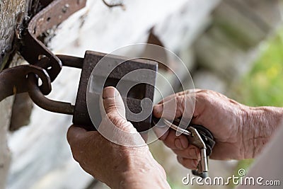 Old man hands holding metal vintage lock and key to open close old wooden door Stock Photo