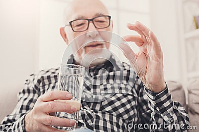 Old man having a glass of water and pills in hand Stock Photo