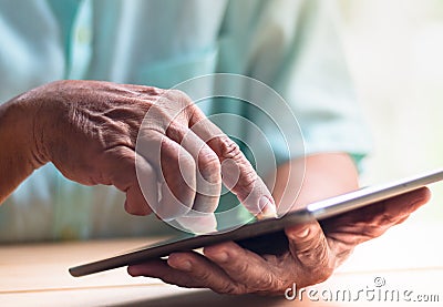 Old man hold tablet with left hand and touch screen with right index finger Stock Photo