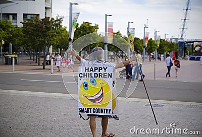 The old Chinese man holding the white board on his body with a smile icon on it with the word says "happy children and smart Editorial Stock Photo