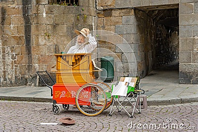 An old man with long white bread plays his street organ Editorial Stock Photo