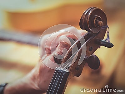 Old man luthier hands tuning aged violin Stock Photo