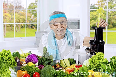 Old man making vegetables juice in the kitchen Stock Photo