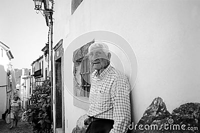 Old man outside his house. In Portugal elderly people often sit outside their houses as a way to pass the time and socialize. Editorial Stock Photo