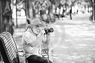 old man relax in park. life during coronavirus lockdown. enjoy the beauty. fear of illness. photographer with camera on Stock Photo