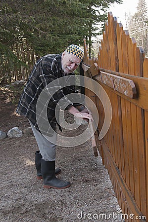 Old man repairing a gate Stock Photo