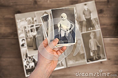 Old manâ€™s male hands hold old retro family photos over an album with vintage monochrome photographs in sepia color, the concept Stock Photo