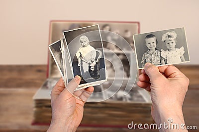 Old manâ€™s male hands hold old retro family photos over an album with vintage monochrome photographs in sepia color, genealogy Stock Photo