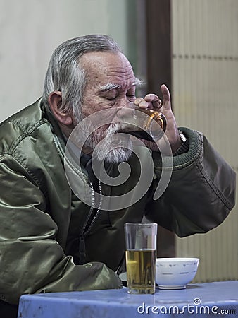Old man savoring the intense pleasure of strong and dark vietnam Editorial Stock Photo