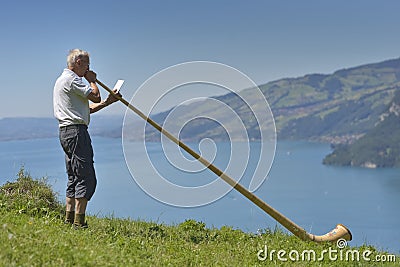 Old man singing at Alpen horn with Thun lake in background Editorial Stock Photo