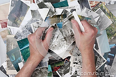 The old man is tearing the old photographs into small pieces to Stock Photo