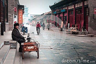 Old man with a tricycle in a street of Pingyao, China. Editorial Stock Photo