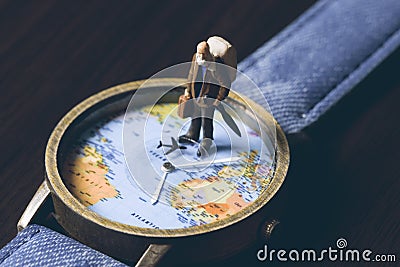 Old man on watches with world map, vintage toned photo. World travel banner. Senior traveler figurine. Stock Photo