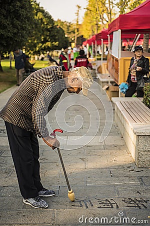 An old man writing Chinese calligraphy in the park Editorial Stock Photo