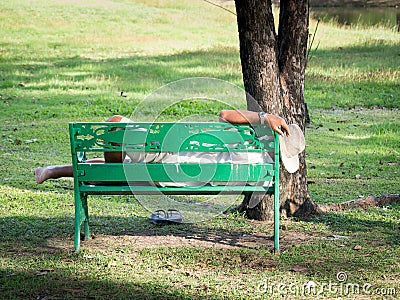 The old man with wrist watch and wearing a white cowboy hat was resting on a green chair in the garden. Stock Photo