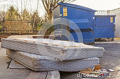 Old mattresses dumped by garbage containers Stock Photo