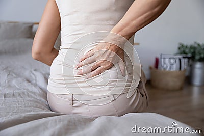 Old mature woman sit on bed touch back feel backpain Stock Photo