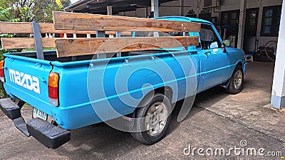 An old Mazda family blue pickup truck parked in front of the house. Editorial Stock Photo
