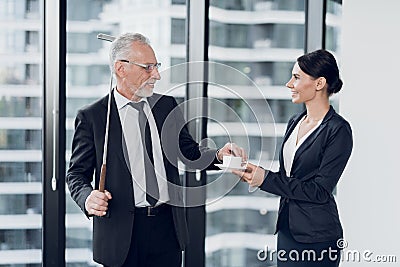 The secretary brought coffee to her boss. He stands in the background of a window with a golf key behind him Stock Photo