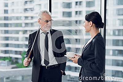 The secretary brought coffee to her boss. He stands in the background of a window with a golf key behind him Stock Photo