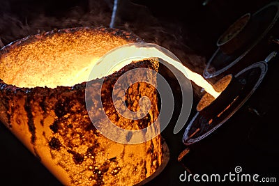 Molten bronze poured into mold by melter in foundry workshop Stock Photo