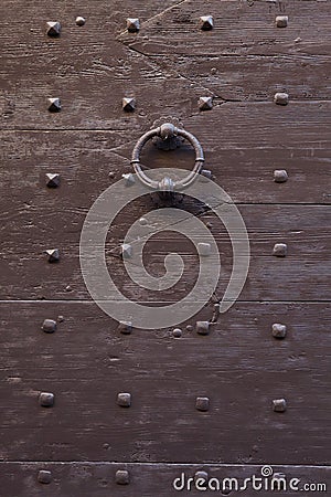 Old metal doorknocker on the brown painted wooden gate fixed wit Stock Photo