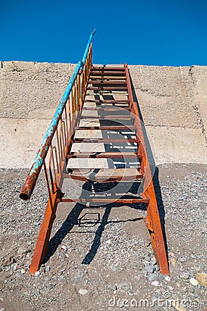 Old metal rusty staircase leading towards sea Stock Photo