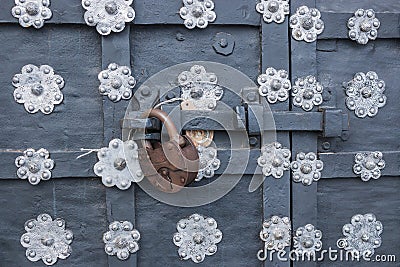 The old metal wrought-iron door is locked with a padlock. Closed metal lock. Stock Photo