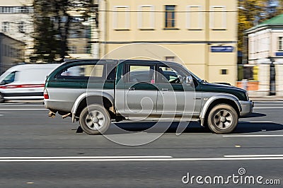 Old Mitsubishi L200 Third generation 4-door pickup is moving fast along a city street Editorial Stock Photo