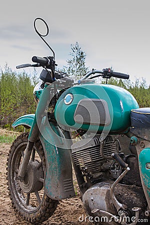 An old motorcycle - partial view of front part with dirty tank with smudges of gasoline and handlebar on off-road Stock Photo