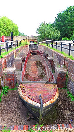 Old narrow boat shell in disused canal lock chamber Stock Photo