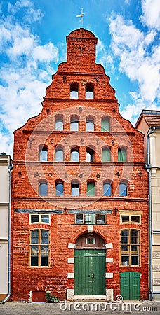 Old narrow gable house facade made of red brick with many small windows in the old town of Wismar Stock Photo