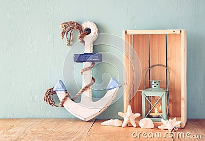 Old nautical wood anchor, lantern and shells on wooden table over wooden aqua background Stock Photo