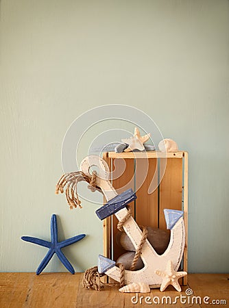 Old nautical wood anchor and shells on wooden table over wooden aqua background Stock Photo