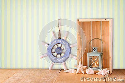 Old nautical wood wheel, anchor and shells on wooden table over retro background Stock Photo