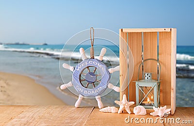 Old nautical wood wheel, anchor and shells on wooden table over sea background Stock Photo